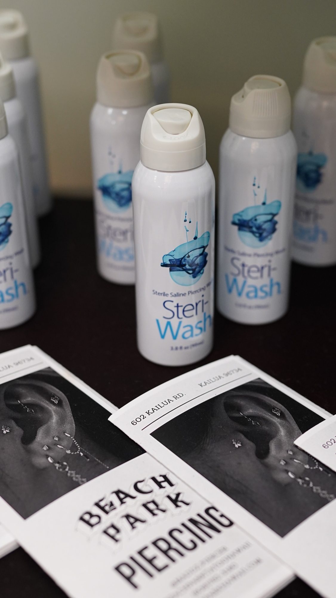 SteriWash sterile saline bottles and Beach Park Piercing branded aftercare cards